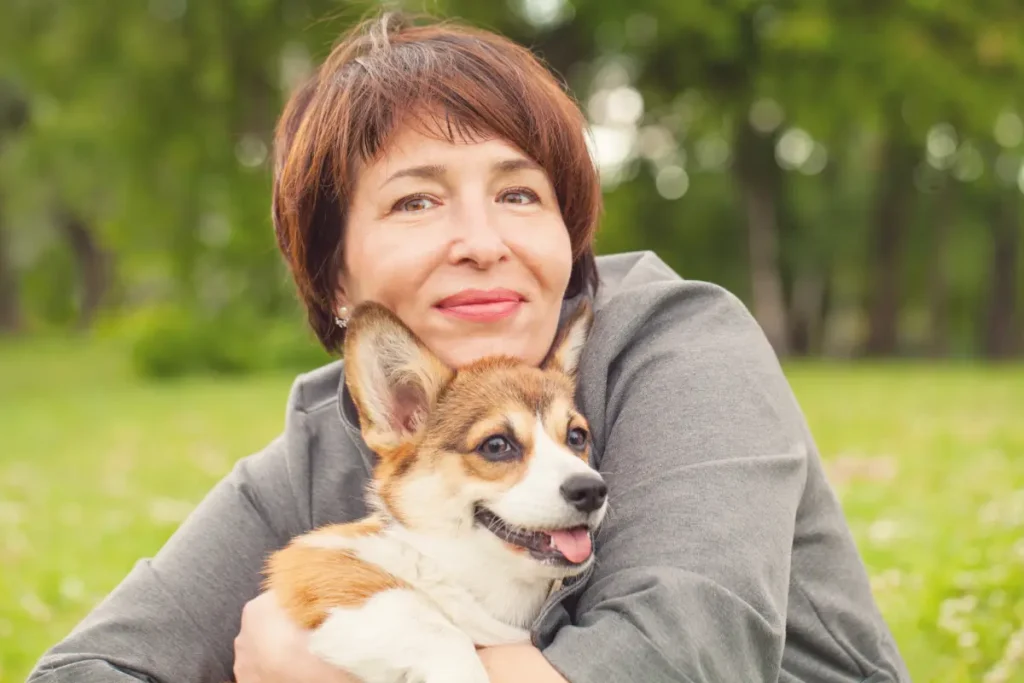 Smiling woman hugging her dog outdoors, representing pet-friendly retirement living at Harmony Place.